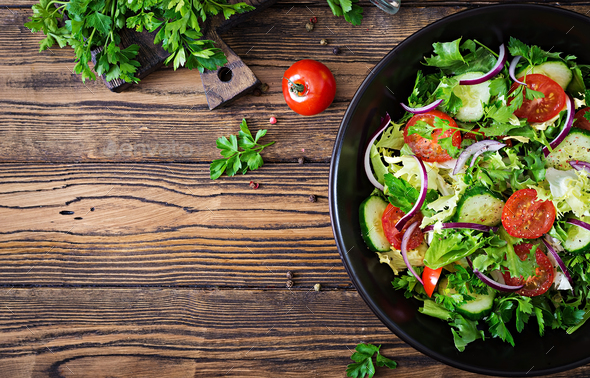 Salad from tomatoes, cucumber, red onions and lettuce leaves. - Stock Photo - Images