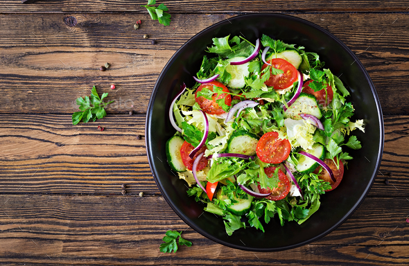 Salad from tomatoes, cucumber, red onions and lettuce leaves. - Stock Photo - Images