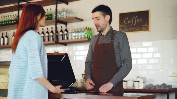 Attractive Young Woman Is Talking To Friendly Male Cashier, Paying for ...