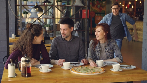 Joyful Man in Casual Clothes Surprising Young Woman on Sudden Arrival in Cafe alt