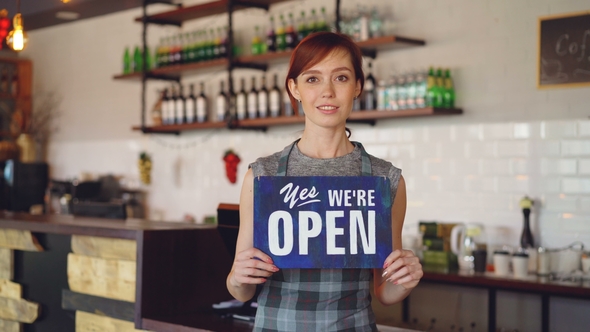 Portrait of Confident Woman Small Business Owner Holding "We Are Open" Sign Standing in Her Coffee alt