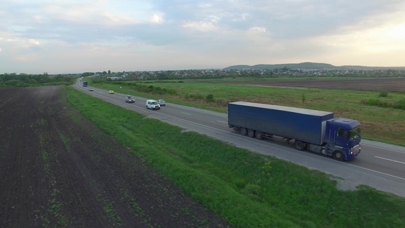 Aerial Shot of Truck Driving a Road Between Fields