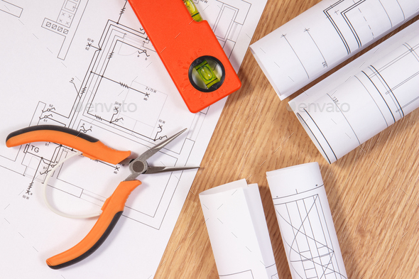 Electrical blueprints or diagrams and orange work tools for use in engineer jobs Stock Photo by ratmaner