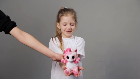 Young Girl Is Happy To Receive a New Toy. Girl with Closed Eyes Waiting for a Holiday Present