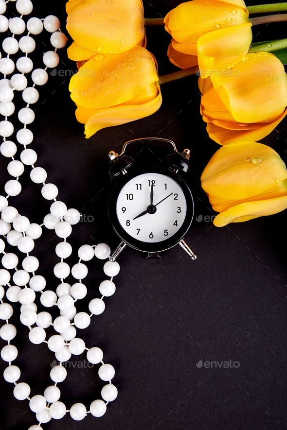 Black alarm clock near bouquet yellow tulips - Stock Photo - Images