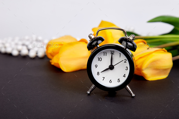 Black alarm clock near bouquet yellow tulips - Stock Photo - Images