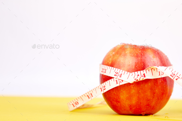 Measuring tape wrapped around a red apple - Stock Photo - Images
