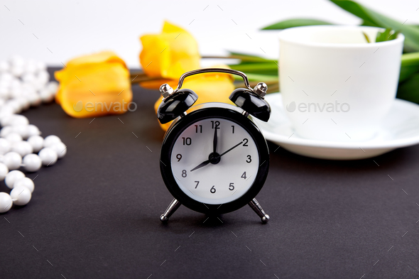 Black alarm clock near bouquet yellow tulips - Stock Photo - Images