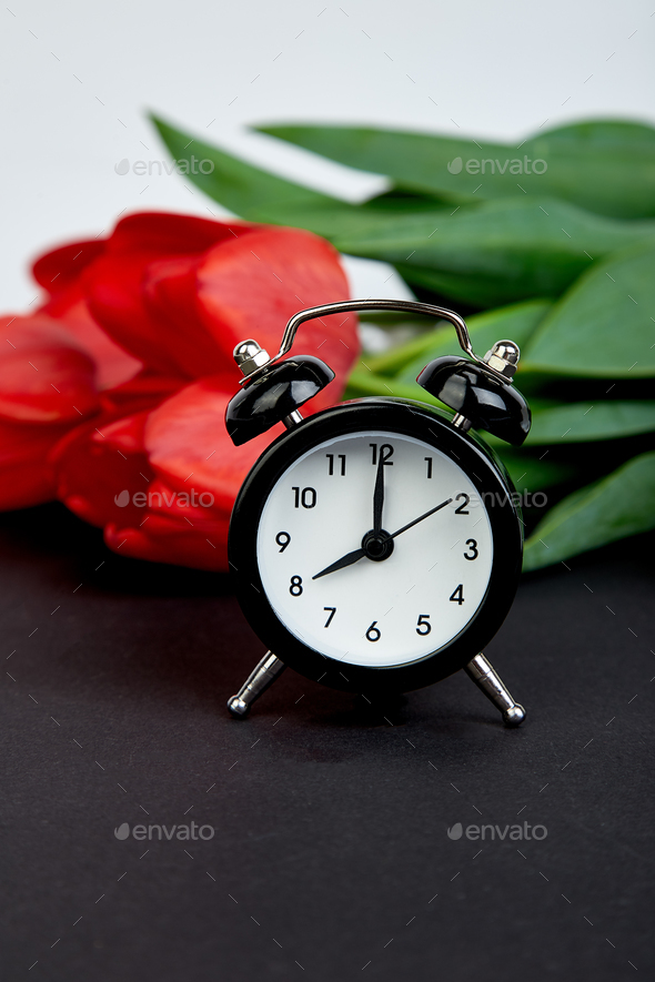 Black alarm clock near bouquet red tulips - Stock Photo - Images