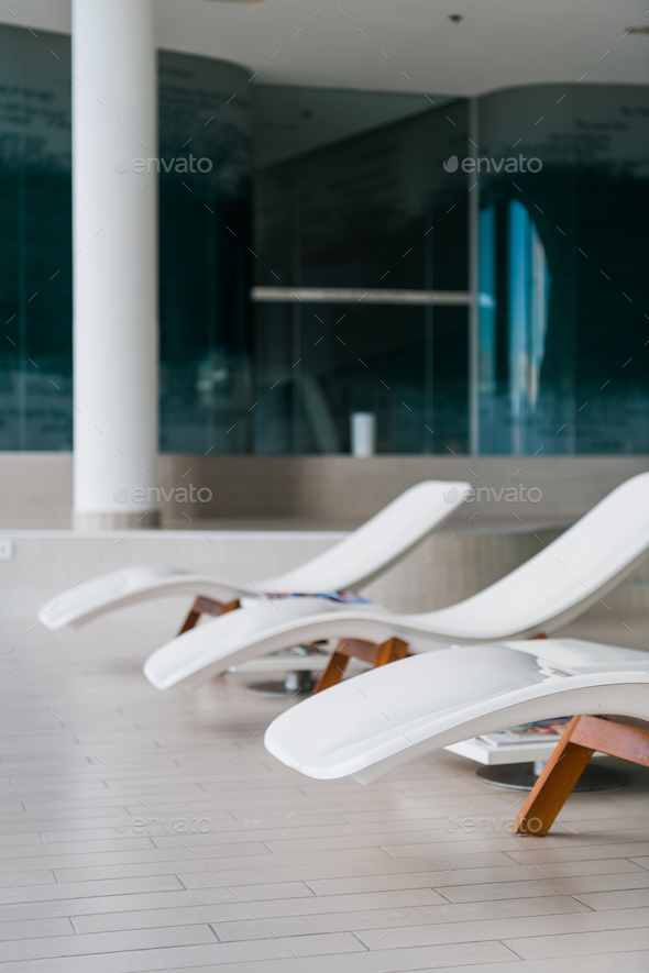 Modern deck chairs at luxury hotel. Private swimming pool for relaxation, with beautiful interior. Stock Photo by romankosolapov