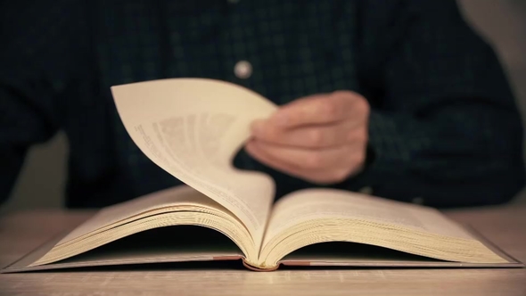 Male Hand Flipping Book Pages During Reading . Man Reading Book alt