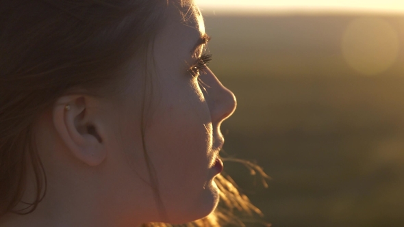 The Face of a Young Beautiful Woman Who Looks at the Setting Sun The Wind Shakes Her Hair alt