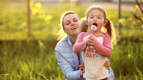 A Sweet Little Girl with Two Tails on Her Head, Along with Her Mother, Is Deliberately Blowing a alt