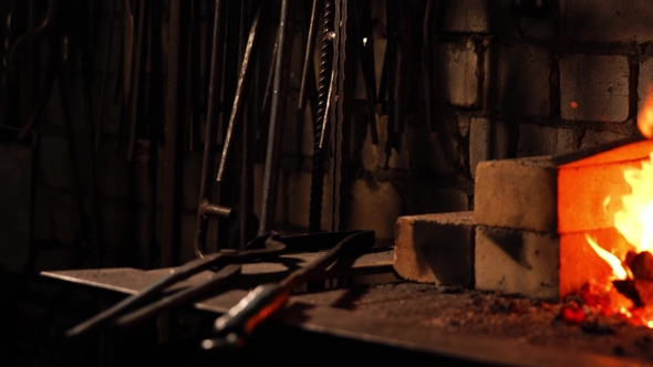 Blacksmith Fanning the Flames of the Furnace Using the Tools Prevents Embers alt