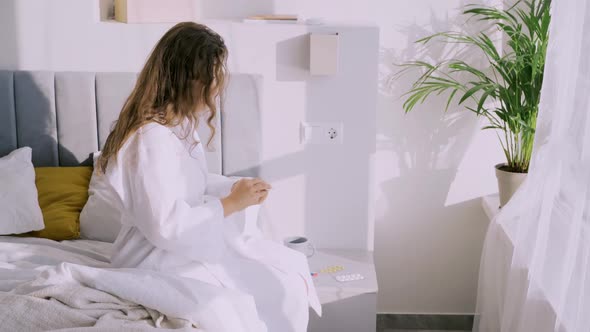 Young Woman Takes Pill Sitting on Bed