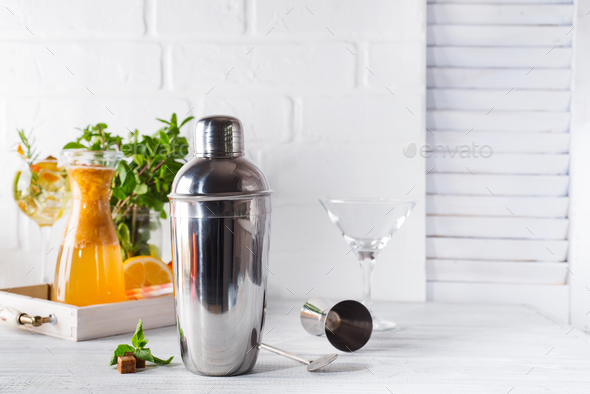 Cocktail shaker, swizzle, tongs and spoon with ice in a bucket for preparing a summer cocktail - Stock Photo - Images