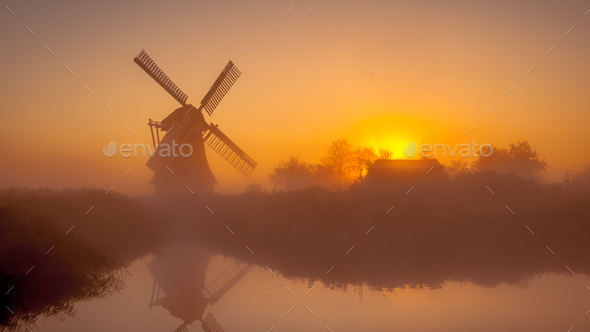 Historic dutch windmill along a canal - Stock Photo - Images