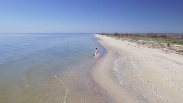 Aerial View of Beautiful Woman Alone in an Amazing and Unspoiled Beach in the Sea Coast