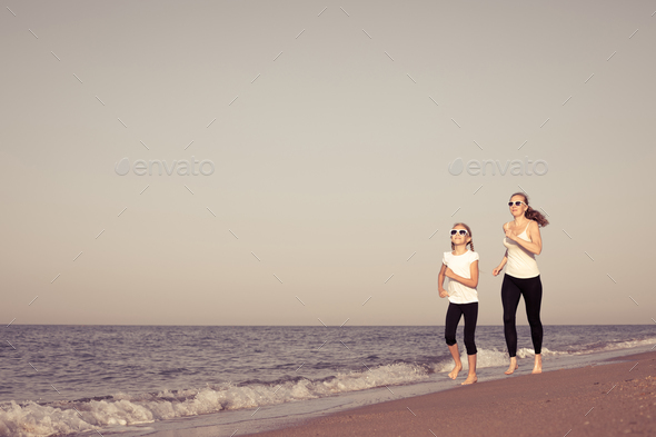 Mother and daughter running on the beach at the day time. - Stock Photo - Images
