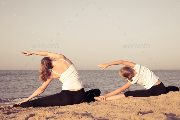 Mother and daughter standing on the beach at the day time. - Stock Photo - Images