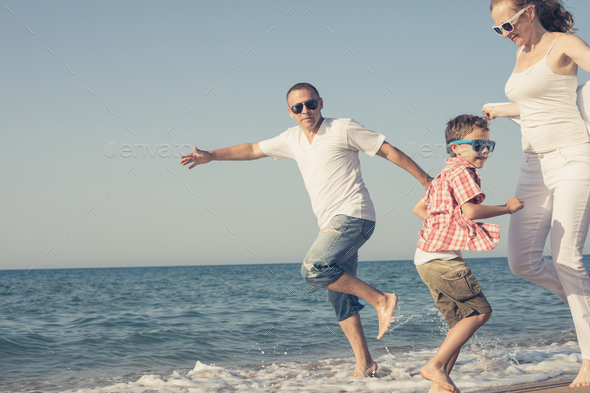 Happy family running on the beach at the day time. - Stock Photo - Images