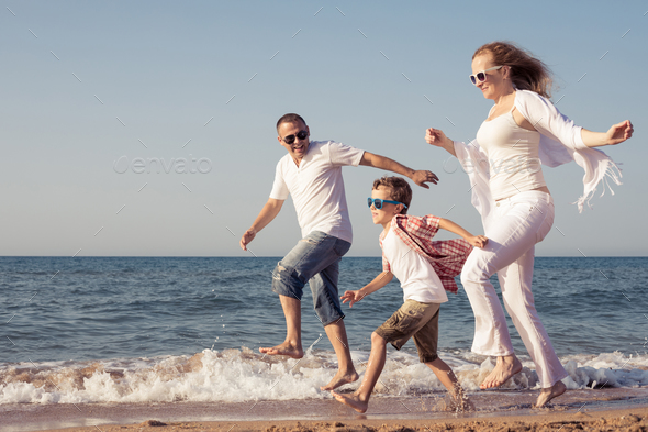 Happy family running on the beach at the day time. - Stock Photo - Images