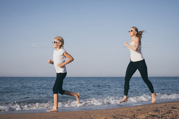 Mother and daughter running on the beach at the day time. - Stock Photo - Images