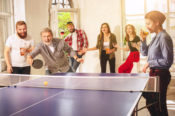 Group of happy young friends playing ping pong table tennis - Stock Photo - Images