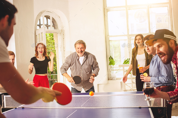 Group of happy young friends playing ping pong table tennis - Stock Photo - Images