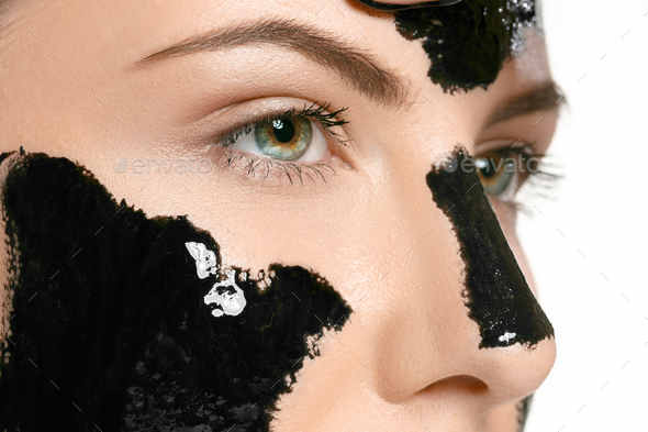 Young beautiful woman applying a mask for the face of the therapeutic black mud. Spa treatment - Stock Photo - Images