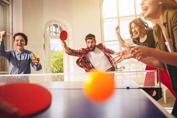Group of happy young friends playing ping pong table tennis Stock Photo by master1305