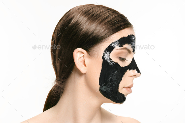 Young beautiful woman applying a mask for the face of the therapeutic black mud. Spa treatment - Stock Photo - Images