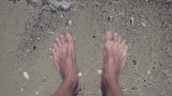 of Male Feet in Clear Sea Water on Beach.