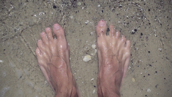 Male Feet in Clear Sea Water on Beach