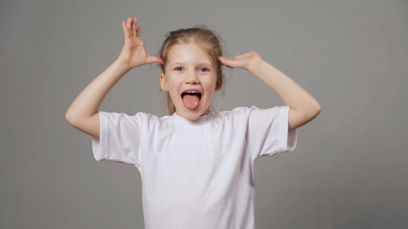 Cute Young Girl Playing the Ape. Funny Girl Showing Grimaces Over Grey Background