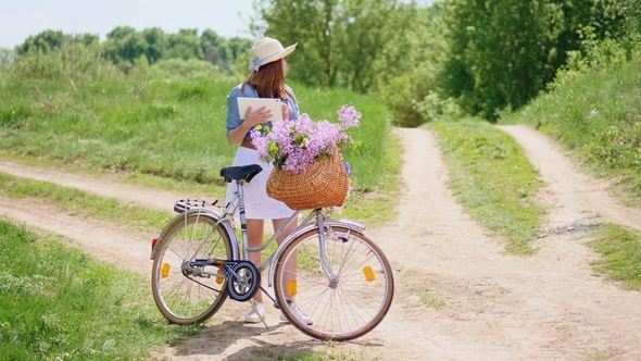 Young Woman Uses a Digital Tablet on the Nature alt