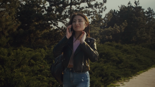 Asian Woman Talking on Mobile Phone in Park alt