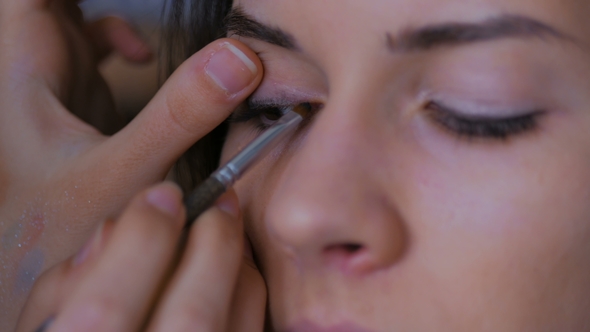 Professional Make-up Artist Applying Eyeliner Around the Entire Eye of Model alt