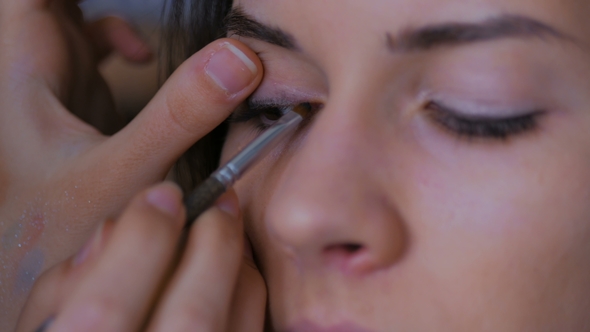 Professional Make-up Artist Applying Eyeliner Around the Entire Eye of Model