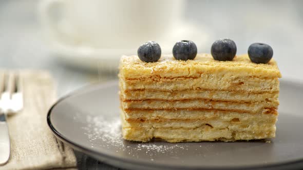 Cream Puff Pastry Cake, Decorated with Four Blueberries, Is Being Powdered with Icing Sugar. UHD alt
