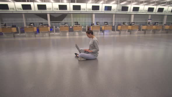 Woman Work on Laptop and Waiting for Flight in Airport in Terminal on the Floor alt