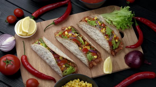 The Mexican Dish of Tako Corn Flat Cake with Vegetable Filling on a Wooden Board on Black Background alt