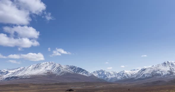 Timelapse of Sun Movement on Crystal Clear Sky with Clouds Over Snow Mountain Top alt