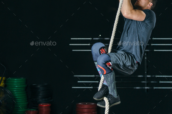 Man doing rope climb exercise - Stock Photo - Images