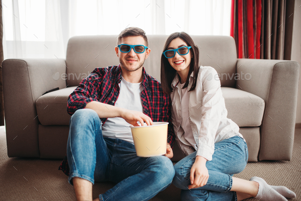 Couple sitting on floor and watch tv with popcorn - Stock Photo - Images