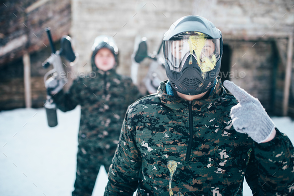 Paintball player points finger at splattered mask - Stock Photo - Images