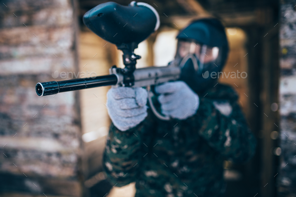 Paintball player with marker gun, front view - Stock Photo - Images
