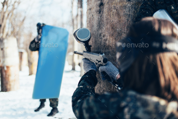 Paintball player shooting at enemy with the shield - Stock Photo - Images