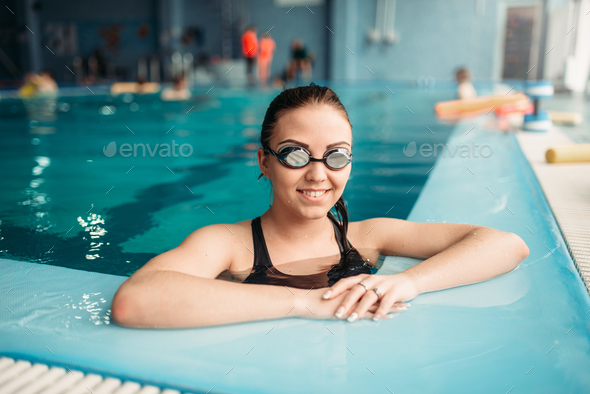 Smiling female swimmer in goggles swims in pool Stock Photo by NomadSoul1
