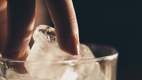 Female Fingers Take Ice From a Glass
